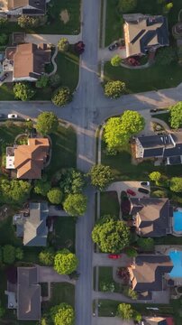 Vertical screen. Aerial perspective of suburban area in Johnson City, Tennessee, highlighting tree-lined streets, various residential homes, vibrant green lawns illuminated by warm golden hour light