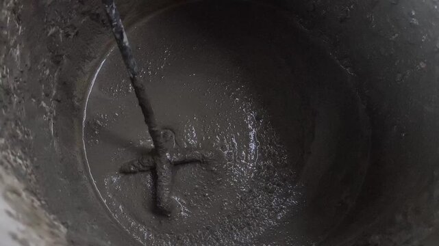 Dark mixture swirls within metal container