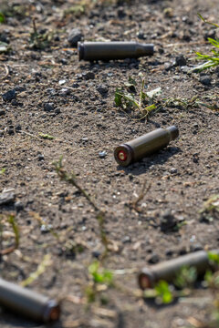 Empty spent bullet casing shell on dry ground dirt closeup macro texture background.
