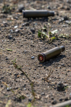 Empty spent bullet casing shell on dry ground dirt closeup macro texture background.
