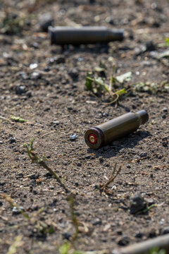 Empty spent bullet casing shell on dry ground dirt closeup macro texture background.
