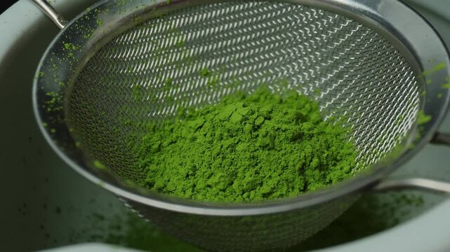 Matcha green tea is sift through a sieve.