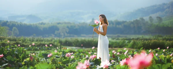Fotobehang Lotusbloem Woman in White Dress Holding Lotus Flower at Vietnam Pond  © Buyanskyy Production