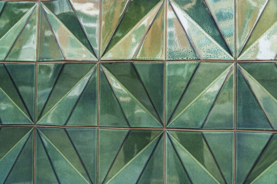 View of geometric green ceramic tiles with a faceted triangular pattern on a wall in London, England, United Kingdom.