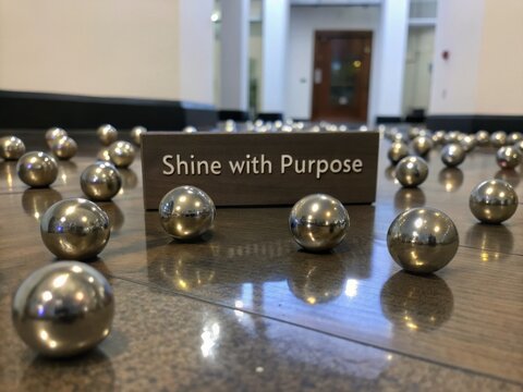Polished metallic spheres reflecting 'Shine with Purpose' message