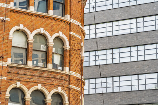 View of the historic red brick facade of Liverpool Street Station contrasting with a modern glass office building in London, England, United Kingdom.
