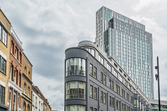 View of modern architecture near Liverpool Street, featuring a sleek dark grey building with curved glass windows and a towering glass skyscraper in London, England, United Kingdom.