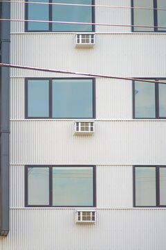 Modern building with multiple windows and air conditioning units on a sunny day.