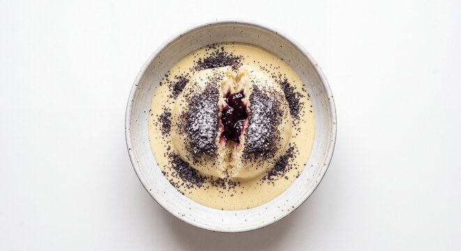 Traditional Austrian Germkn&ouml;del yeast dumpling with plum jam filling in vanilla sauce topped with poppy seeds