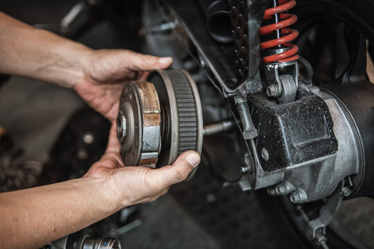 technician installing the outer clutch drum on a scooter engine. This image shows the professional assembly process of the motorcycle's centrifugal clutch and transmission system.