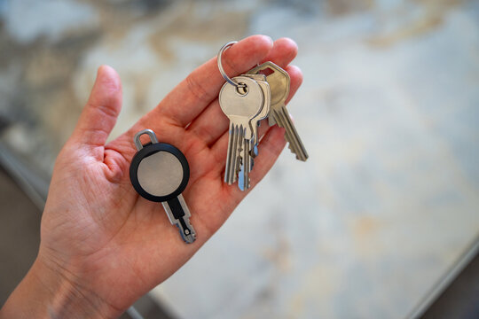 Hands holding traditional metal keys and an RFID key fob together. Concept of transition from mechanical locks to electronic access control and smart security technology