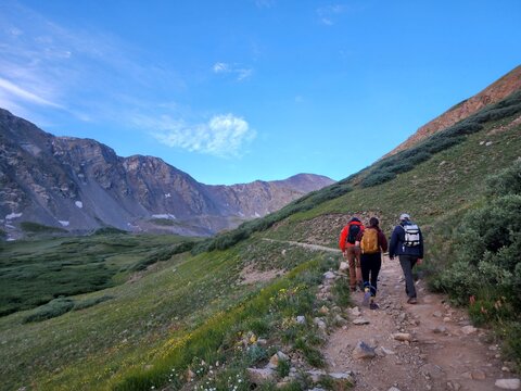 Silver Plume, Colorado, United States - 23 July 2022: View of hikers on the Grays and Torreys Summer Trailhead with alpine meadows, rocky slopes, and a clear blue sky.