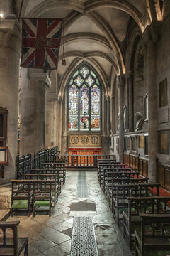 Oxford, England, United Kingdom - 24 July 2026: View of the interior of a historic church featuring stone arches, stained glass windows, wooden pews, and a hanging Union Jack flag.