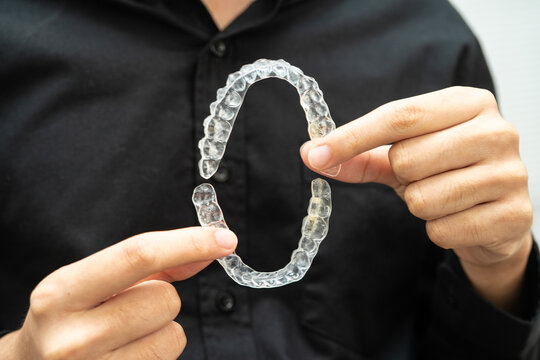Man holding invisible aligner orthodontic retainer for dental teeth straightening.