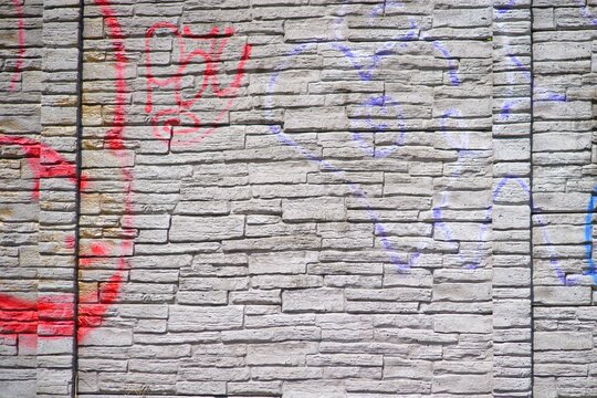 Red and blue spray paint graffiti markings on concrete highway noise barrier wall