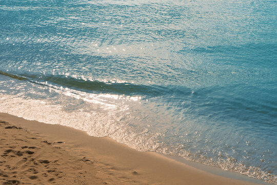 Tranquil blue sea water and golden sand beach with sunlight reflection at Rayong, Thailand