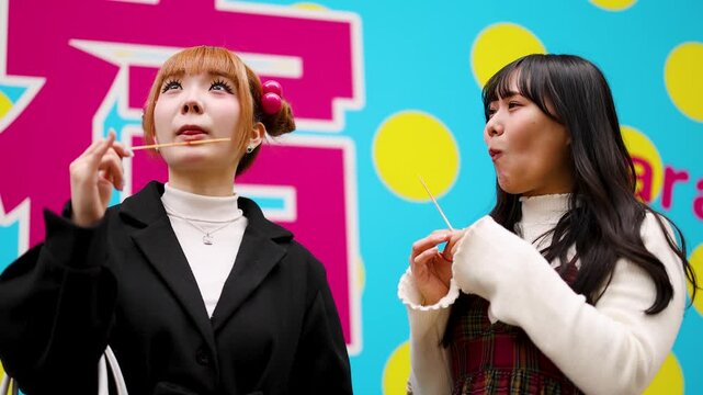 Two Young Women Eating Tanghulu Fruit Skewers in Harajuku Tokyo