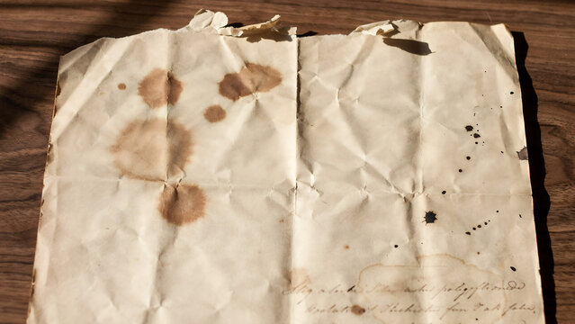 Old vintage paper texture with stains and creases on a dark wooden background antique weathered parchment document with copy space for text