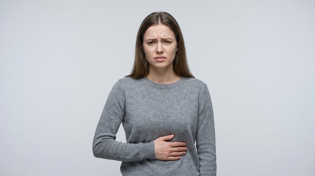 Young woman holding her abdomen in pain with copy space