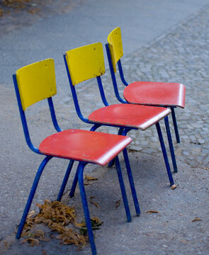 Row of Vintage School Chairs in Vibrant Primary Colors on an Urban Sidewalk