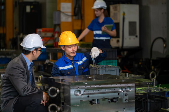 Asian industrial worker is checking the setup value of metal casting machine inside automobile factory for safety industry construction