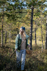 Obraz premium Mature woman strolling through forest, physical activity outdoors and healthy living, female solo hiking in woodlands, walking making way on trekking path in thickets, getaway in nature.