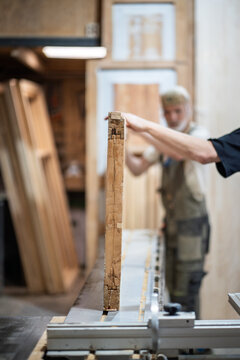 Workflow in private restoration workshop, skillful carpentry workers carefully placing vintage wooden door at workbench, professional repair and renovation service, woodworking studio working process.