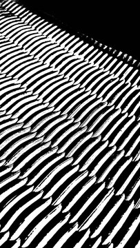 Black and white macro background featuring a regular wavy texture pattern. Parallel lines with strong light and shadow contrast create a modern abstract surface for design projects.