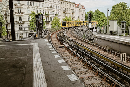 Berlin, Germany - 05 June 2026: View of the yellow U-Bahn train traveling along the elevated tracks in Berlin, with historic buildings and green trees in the background.