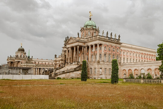 Potsdam, Germany - 04 June 2026: View of Neues Palais featuring its grand baroque architecture, ornate statues, and expansive park grounds under a cloudy sky.
