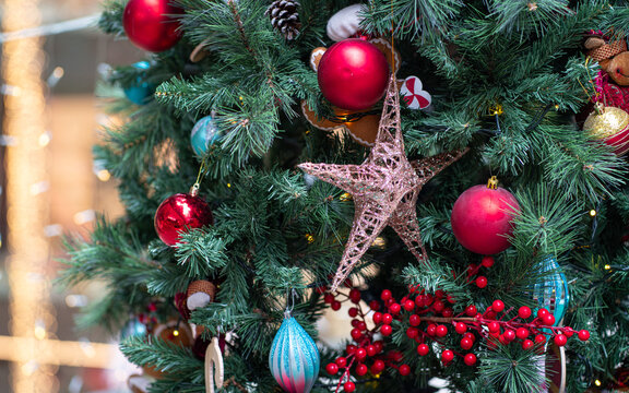 Colorful christmas deco and ornaments of balls and star hanging on tree.