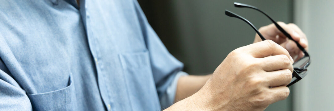 Asian elderly senior man with eyesight issue, concept image of aging eye sight, vision deterioration, elderly vision problem, hand holding eyeglasses closeup shot, home indoor scene