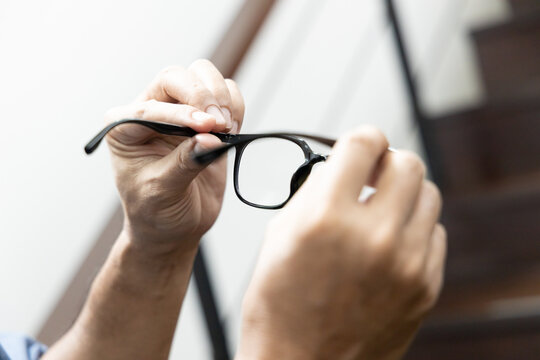 Asian elderly senior man with eyesight issue, concept image of aging eye sight, vision deterioration, elderly vision problem, hand holding eyeglasses closeup shot, home indoor scene