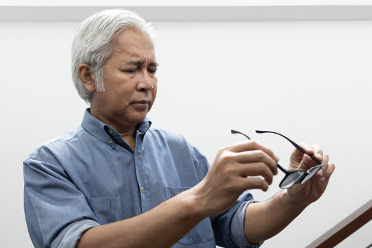 Sad Asian old senior man with eyesight problem, concept image of aging eye sight, vision deterioration, eyesight impair, optical problem with his eyeglasses, retina care, eye care