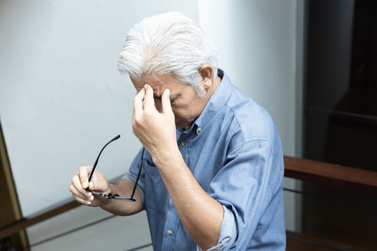Asian elderly senior man with eyesight issue, concept image of aging eye sight, vision deterioration, cataract, glaucoma, eyesight impair, optical problem with eyeglasses, home indoor eye care