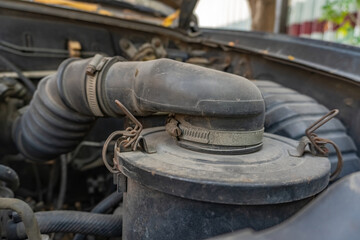 Fototapeta premium Close up of a car air filter housing and intake hose with metal clamps inside an engine bay, highlighting classic vehicle maintenance and repair work.