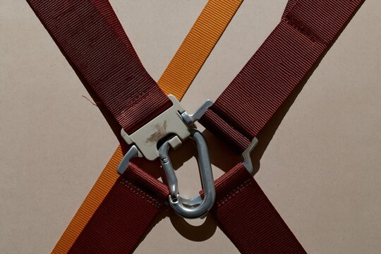 Fall-arrest harness with a forged snap hook and buckle, featuring rugged woven webbing and stitched seams for height safety training, with copy space
