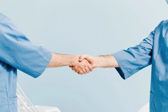Handshake between a dentist and a patient in a bright modern clinic with soft lighting, airy atmosphere and generous copy space for branding