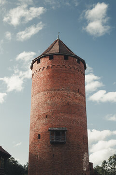 Sigulda, Latvia - 25 July 2023: View of the historic red brick tower of Sigulda Castle against a blue sky with scattered clouds.