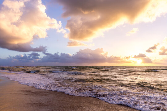 Beautiful cloud coastline background. Fiery orange sunset sky. Amazing sunrise on the beach in Miami. Fantastic landscape when sun setting over horizon on a cloudy day.