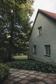 Sigulda, Sigulda Municipality, Latvia - 25 July 2023: View of a historic house with a tiled patio and lush greenery in the garden.