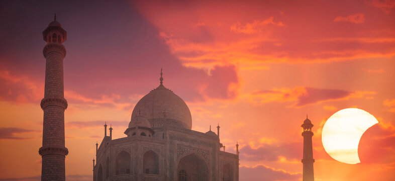 Taj Mahal in Agra against pink and orange sunrise with solar eclipse and copy space