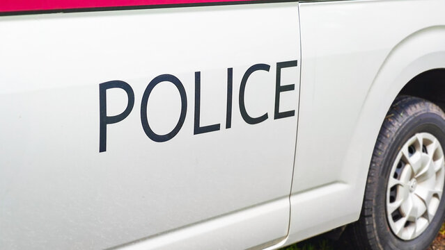 Police Vehicle: Close-up view of the side of a Thailand police patrol car. The word POLICE is clearly visible on the side of a white vehicle, hinting at law enforcement and security. 