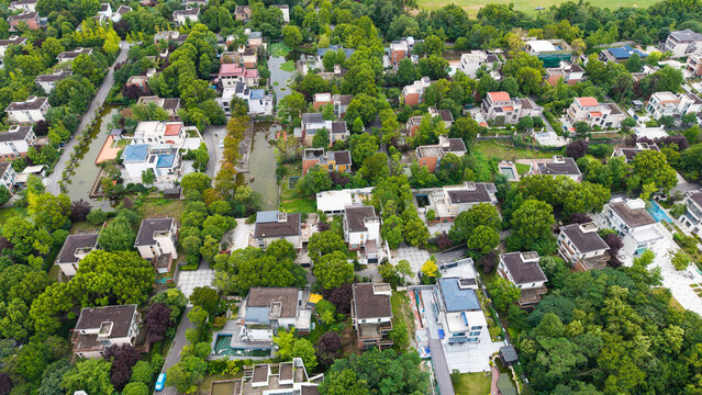 Aerial top‑down view of green‑surrounded suburban villa residential area