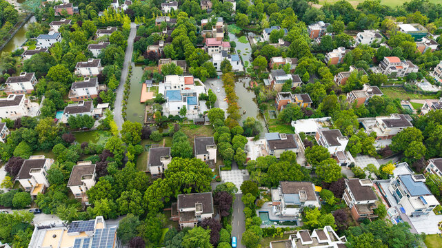 Aerial top‑down view of green‑surrounded suburban villa residential area