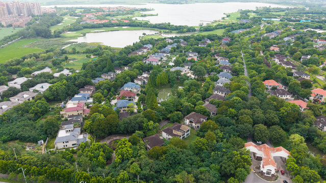 Aerial top‑down view of green‑surrounded suburban villa residential area
