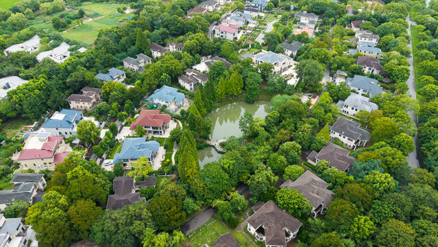 Aerial top‑down view of green‑surrounded suburban villa residential area