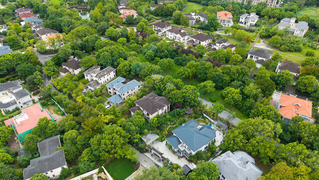 Aerial top‑down view of green‑surrounded suburban villa residential area