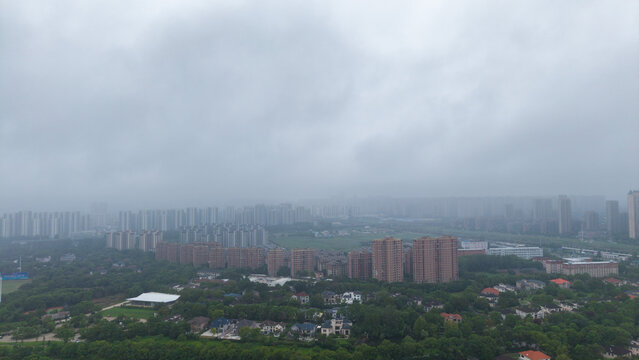 Overcast high‑angle city overlook of urban residential buildings shrouded in mist