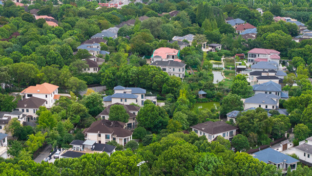 Aerial top‑down view of green‑surrounded suburban villa residential area